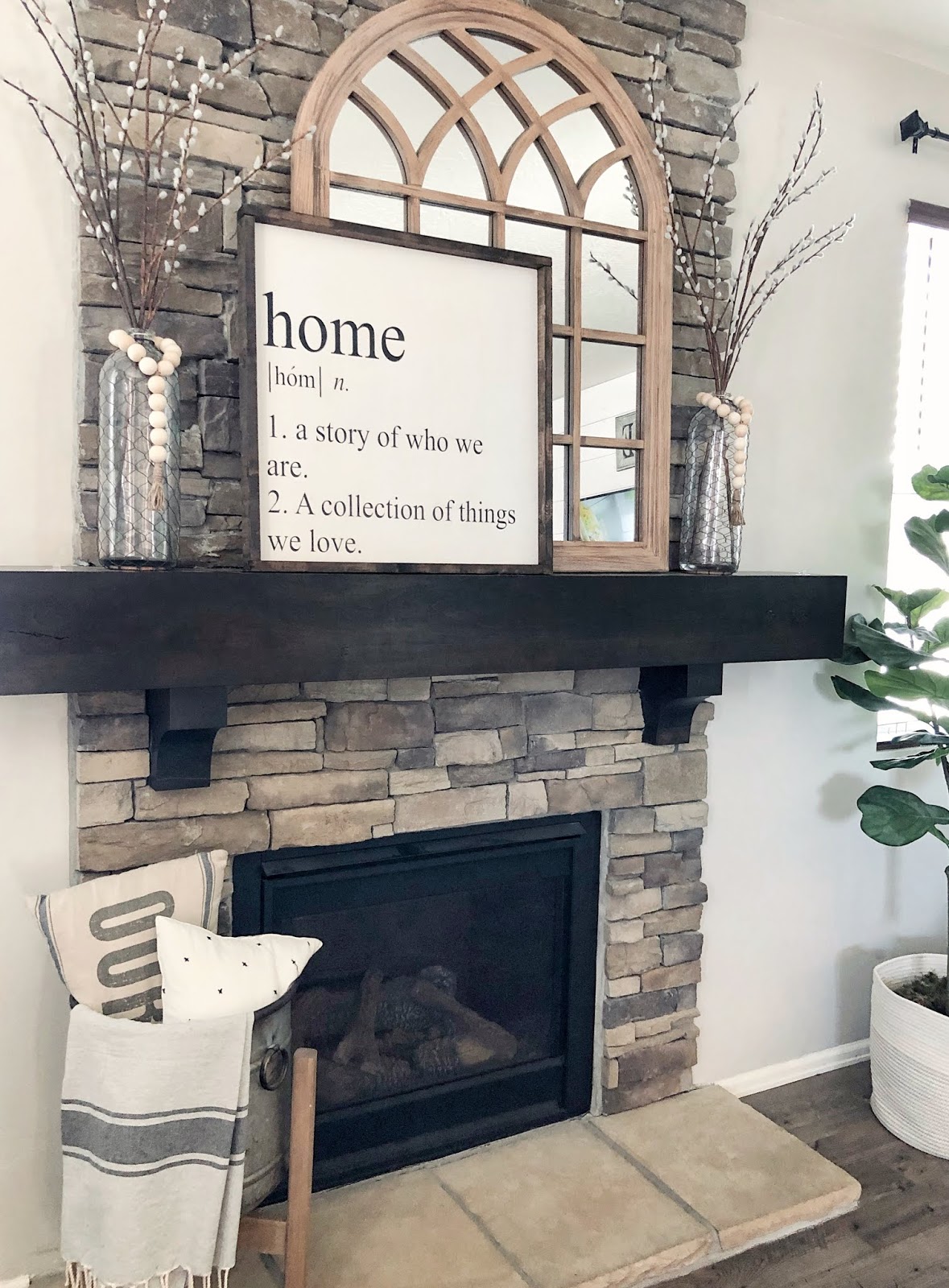 farmhouse styled fireplace, arched mirror, wood sign, glass vases