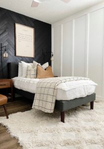 bedroom with black wood wall and white bedding